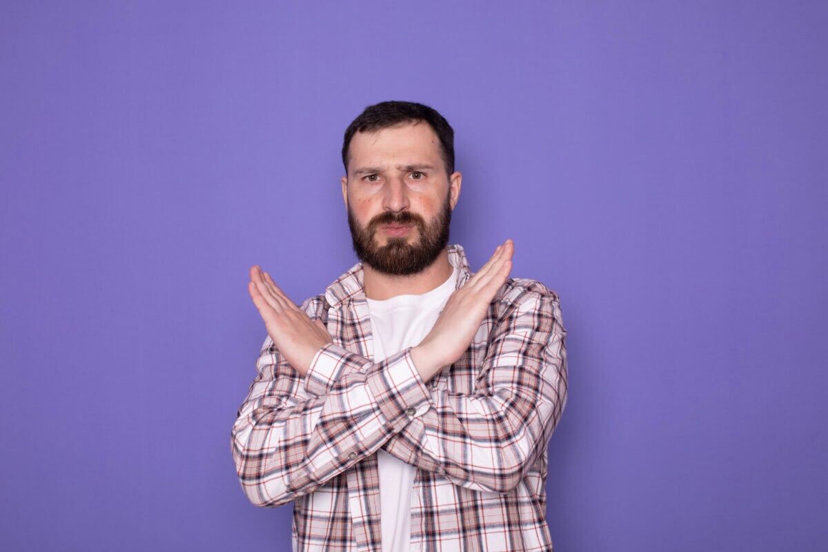 man crosses arms and hands to make stop sign