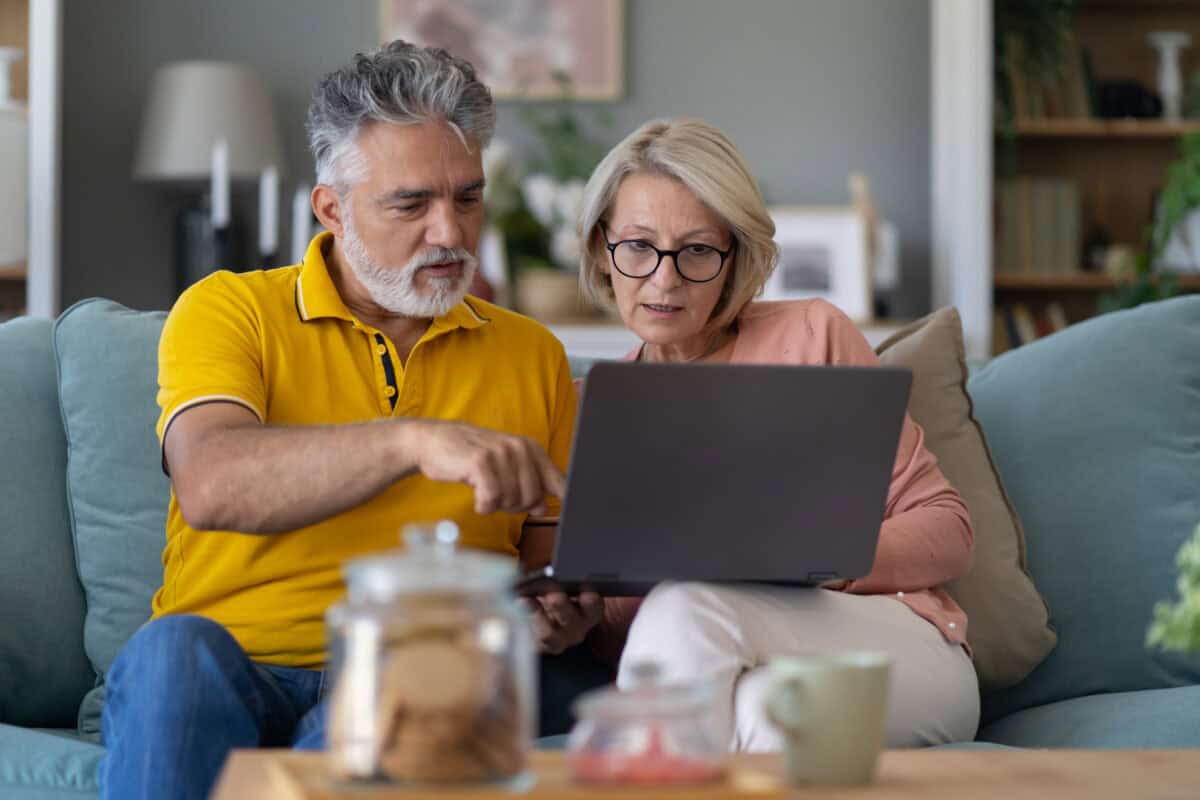 middle-aged couple work together on laptop
